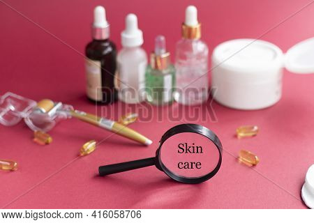 Magnifying Glass Against The Background Of Blurred Face Serums And Dermoroller