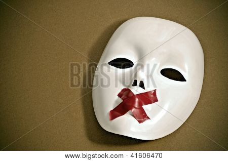 maschera bianca con nastro rosso strisce formando una croce nella sua bocca su uno sfondo marrone
