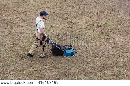 Scarifying Lawn With Scarifier, Man Gardener Scarifies The Lawn And Removal Of Old Grass