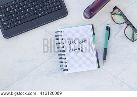 We Are Hiring. Job Recruting Concept. Words We Are Hiring In Notebook On The Working Table. Top View