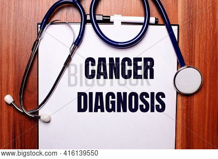 On A Wooden Background Lies A Stethoscope And A Sheet Of Paper With The Inscription Cancer Diagnosis