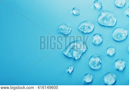 Drops Of Gel With Hyaluronic Acid In The Form Of A Smear Of Glossy Texture On A Blue Background.