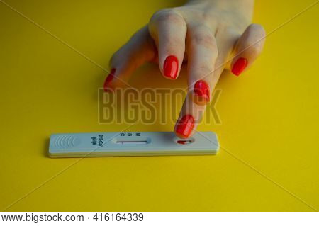 Coronavirus Test On A Yellow, Bright Background. Medical Analysis. A Girl With A Bright Red Manicure