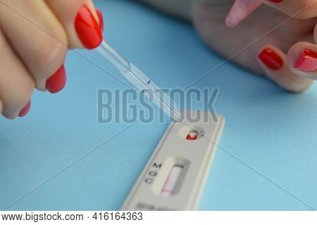 Test For Coronavirus On A Blue Background. Girl With A Bright Red Manicure Makes A Blood Test. A Dro