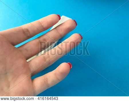 On A Blue Matte Background Hand. Girl's Fingers With Bright Red Manicure On The Medical Table. Plan