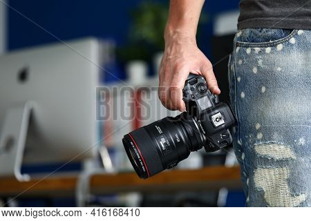 Male Hand Holding Brand New Mirrorless Digital Camera Canon R5 Closeup