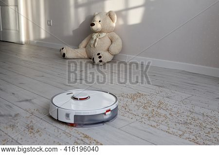 White Robot Vacuum Cleaner Effectively Removes Grain From The Laminate Leaving A Clean Path Behind