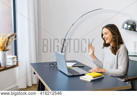 Side View Smiling And Friendly Female Office Employee In Informal Casual Wear Using Laptop For Video