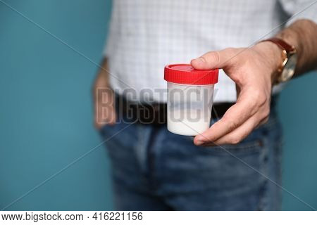 Donor Holding Container With Sperm On Turquoise Background, Closeup. Space For Text