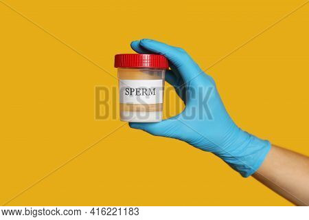 Scientist Holding Container With Sperm On Yellow Background, Closeup