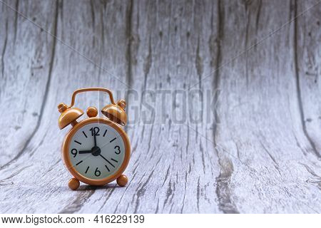 Orange Old Retro Style Alarm Clock On Wooden Background. Alarm Clock Shows Nine O`clock