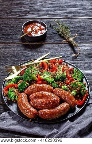 Italian Cotechino Pork Sausages Braised With Brown Lentils, Red Pepper, And Broccoli Served On A Bla