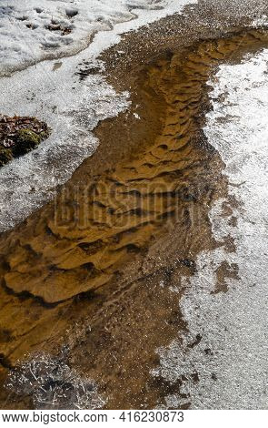 Curved Streambed With A Patterned Bottom And Icy Banks During The Spring Thaw