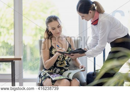 Tourist Woman Going To Fill And Sign Hotel Check In Registration Form At Reception Counter, Kundense