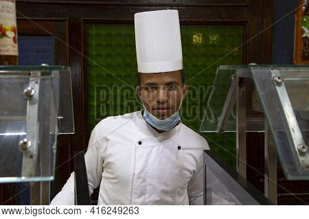Portrait of a dark-skinned male chef at the counter at the food distribution, serving staff in a res
