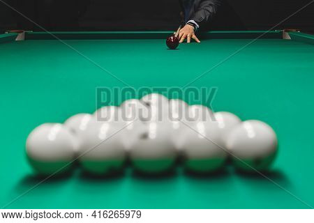 Focus On The Hand Of A Man In A Suit Aiming For A Kiy In A Pile Of White Billiard Balls. Draw Of The