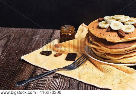 Pancake On A Wooden Board, In The Dark, With Bananas And Chocolate