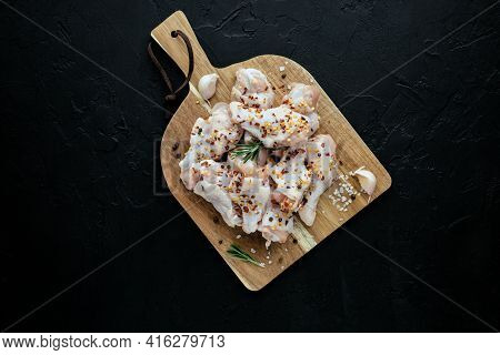 Raw Chicken Wings On Cutting Board With Ingredients For Cooking At Black Background. Fresh Uncooked 
