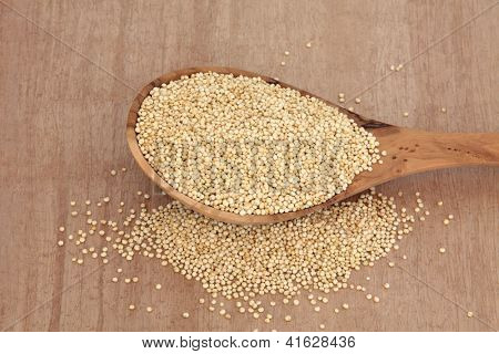 Bir zeytin tahta kaşık papirüs arka plan üzerinde Quinoa tahıl.