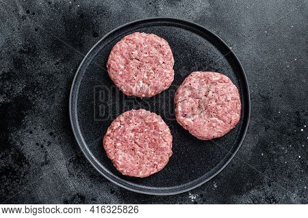 Raw Chicken Turkey Patty, Minced Meat Cutlets On A Plate With Thyme. Black Background. Top View
