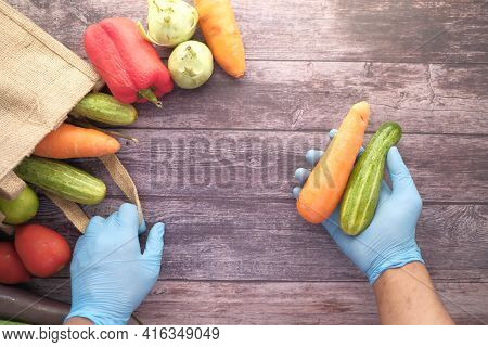 Hand In Gloves Taking Vegetable Out From A Reusable Bag Vegetables Top View