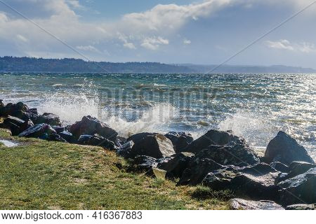 Back Rocks Lin The Shore On A Windy Day At Satlwater State Park In Washington State.
