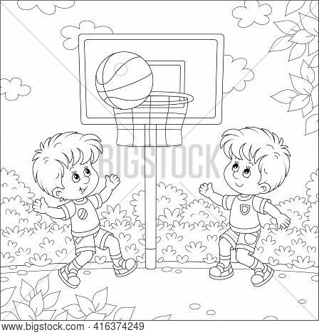 Cheerful Little Kids Playing Basketball With A Big Ball On A Sports Ground In A Park On Summer Vacat