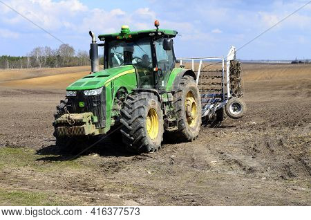 A Large Modern John Deere Tractor Tows A Cultivator In A Field