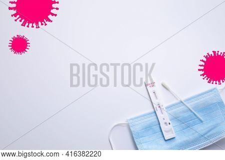 Rapid Coronavirus Test And A Medical Mask On The White Background With Pink Coronavirus Silhouettes.