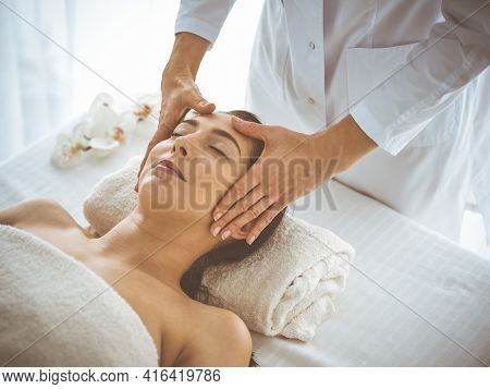 Beautiful Brunette Woman Enjoying Facial Massage With Closed Eyes Comfortable And Blissful. Relaxing