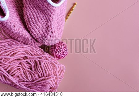 Skein Of Pink Yarn With Crochet And Knitted Shoes On A Colored Background Needlework On The Backgrou