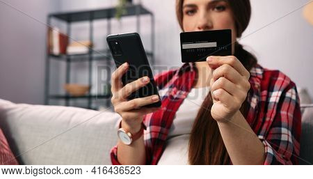Lets Buy This One. Young Brunette Woman Sitting At The Sofa At Home, Holding Credit Card And Doing O