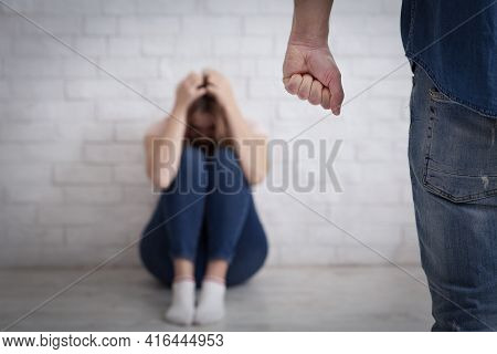 Domestic Violence, Tyranny And Beating. Terrified Woman Covers Her Head With Hands And Sits On Floor