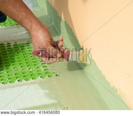 Worker Applies Waterproofing With A Small Brush