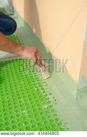 Worker Applies Waterproofing With A Small Brush