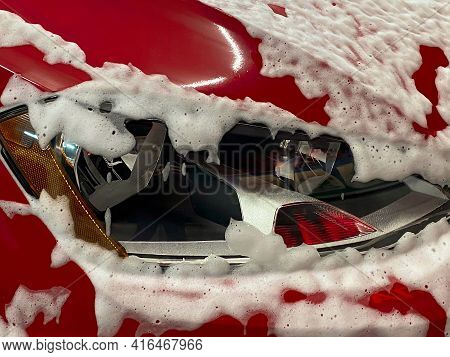 Front Right Wheel Of A Red Car On Which Foam Is Applied To Wash A Car At A Self-service Car Wash.