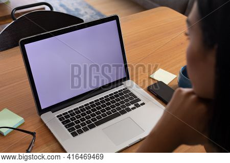 Mixed race gender fluid man working at home making video call using laptop, copy space screen. staying at home in isolation during quarantine lockdown.