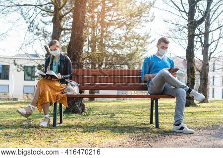 Woman and man in social distancing sitting on bench