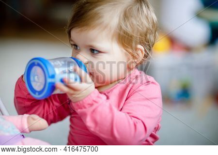 Cute Adorable Baby Girl Holding Nursing Bottle And Drinking Formula Milk Or Water. First Food For Ba