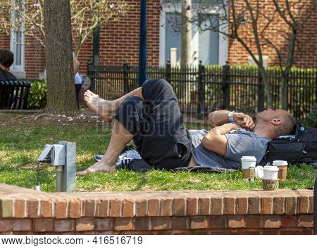 Frederick, Maryland, Usa 04-07-2021: A Young Homeless Man Wearing Hospital Bracelet Is Basking On Th