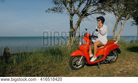 Woman On Red Motorbike In White Clothes Drive On Forest Road Trail Trip. One Girl Caucasian Tourist 