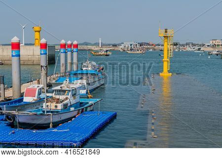Pyeongtaek, South Korea; April 6, 2021: Fishing Boats Moored To Dock At Jeongok Port With Yellow Lig