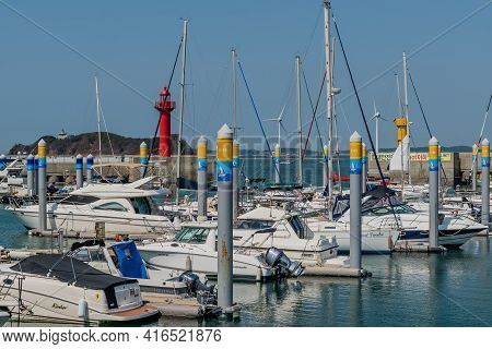 Pyeongtaek, South Korea; April 6, 2021: Yachts Moored At Jeongok Port Marina With Red Lighthouse In 