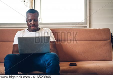 Young Black African Man Relaxing Using Laptop Computer Working And Video Conference Meeting At Home.
