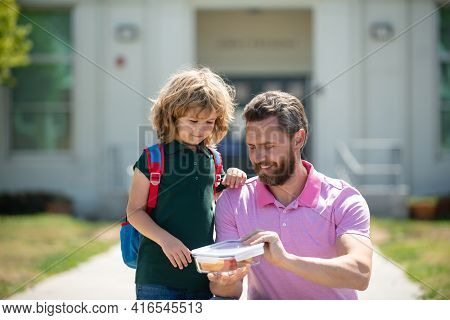 Parent And Pupil Of Primary School Schoolboy With Backpack. Schoolboy And Parent In Shirt Holding Lu