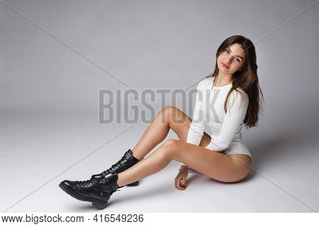 Beautiful Young Woman With Dark Hair In White Body Sits On The Floor
