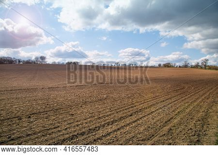 Plowed Agricultural Spring Field During Sunny Day, Dramatic Sky, Soil Texture Close Up. Rural Scene.