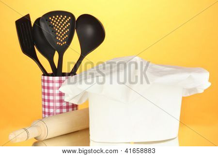 Kochmütze mit Löffel und Federballschläger auf orange Hintergrund
