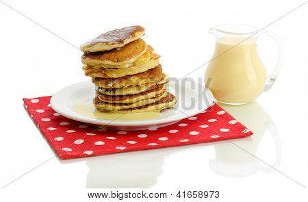 หวาน pancakes บนแผ่นกับนมข้นที่แยกต่างหากบนพื้นสีขาว