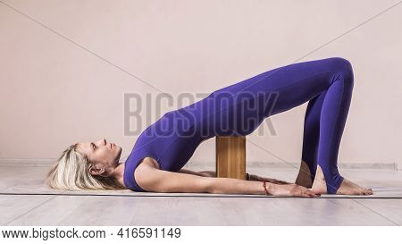 Blonde Woman Practicing Yoga, Doing Dvi Pada Pithasana Exercise With Wooden Yoga Block, Exercising O